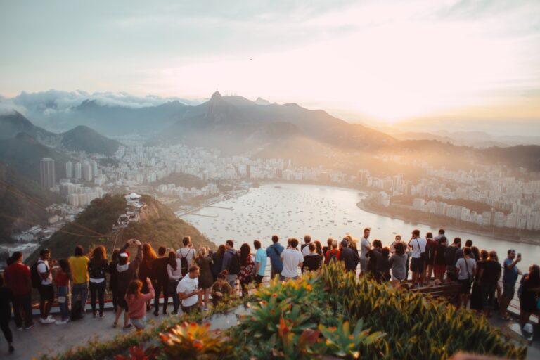 group of people standing facing lake view